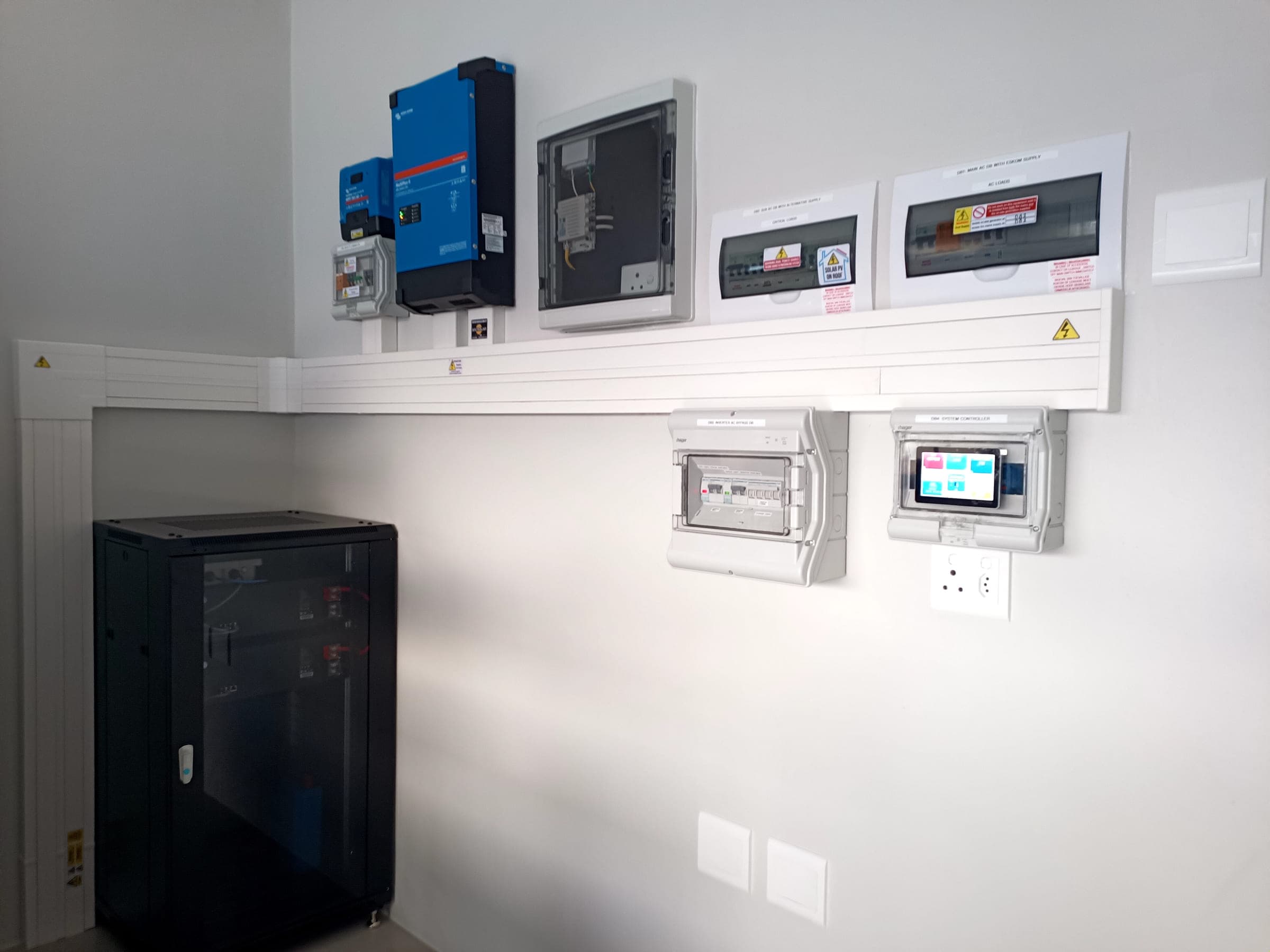 Inverter, distribution boards and system controller mounted and labelled on a plant room wall